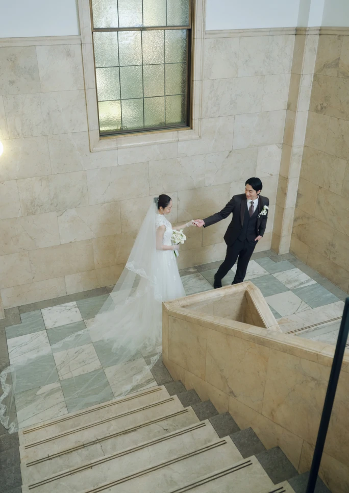 大理石の重厚感のある式場で手を繋ぐ新郎新婦