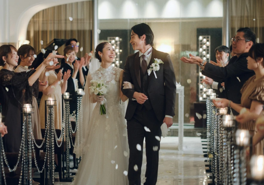 ゲストに祝福されながらフラワーシャワーを受ける新郎新婦